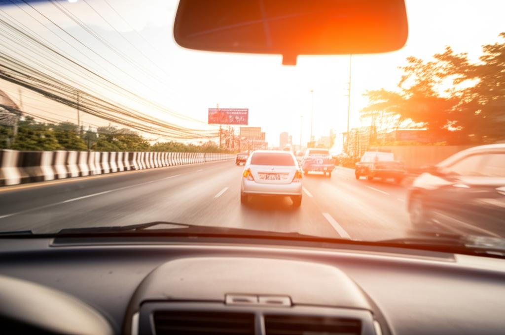 Car driving in busy Bangkok traffic under bright sun