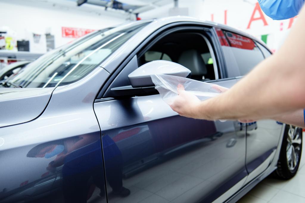 Close-up of car fender with protective film being applied